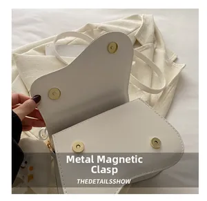 Detail of white saddle bag showing smooth leather and dual metal magnetic closures
