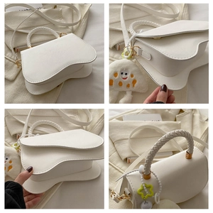 Detail showing asymmetric wave flap, woven handle and plush cloud charm on white crossbody bag