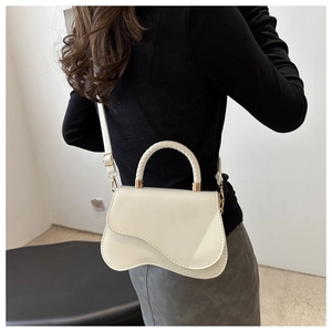 Detail view of cream white crossbody bag with braided handle and wavy base design