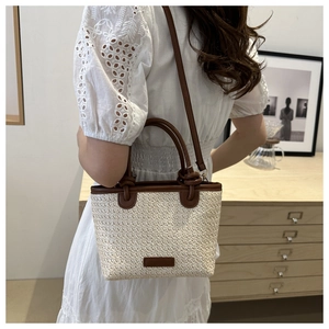Straw and brown leather patchwork tote bag shown on model in a warm minimalist setting