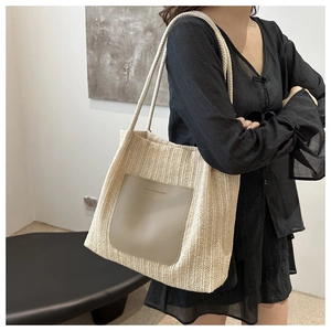 Detail of woven tote bag with leather pocket and contrast shoulder straps on a model