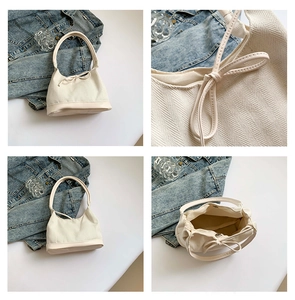 Detail view of cream canvas tote bag showing herringbone texture and leather bow decoration