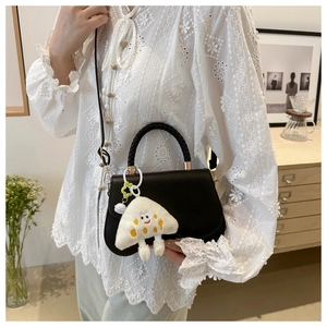 Detail of black crossbody bag with woven handle and cute white plush rice ball pendant