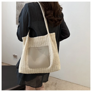 Detail of woven straw tote bag featuring a grey leather pocket with printed fashion text