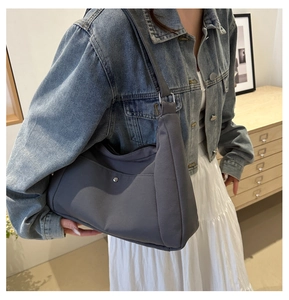 Détail du sac à épaule en nylon gris foncé avec boucle argentée et poche décorative