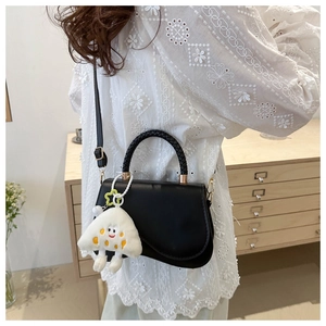 Side view of a black leather crossbody bag worn by a model in a warm home setting