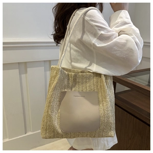 Detail view of woven straw tote bag featuring a leather pocket and rope handles