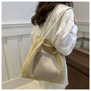 Detail of straw woven tote bag with leather logo patch and braided rope shoulder strap