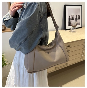 Détail du sac cabas beige avec une poche avant fonctionnelle et bouton-pression en métal