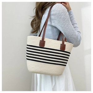 Detail of striped woven tote bag featuring brown leather shoulder straps and textured fabric