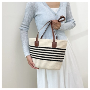 Detailed view of striped straw tote bag featuring brown leather handles and woven texture