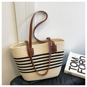 Close-up of woven straw bucket bag showing black stripes and brown leather strap details