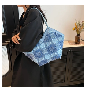 Détail d'un sac cabas en patchwork de denim bleu avec bords effilochés et anses en cuir