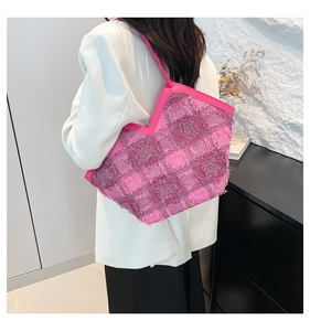 Detailed side view of pink woven tote bag with fringe texture and V-cut design on model