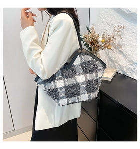 Detail of grey and white plaid tweed tote bag with fringe trim on a model
