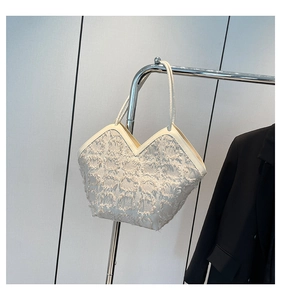 Detail of off-white tote bag featuring fringe texture and unique V-shaped opening design
