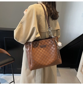 Detail of vintage brown checkered tote bag with baseball charm and metal chain strap