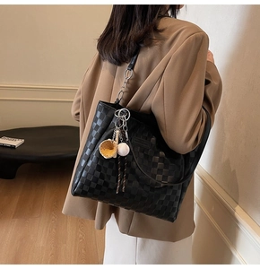 Detail of black checkerboard tote bag with sporty charms and long shoulder straps