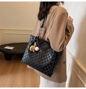 Detail of checkered tote bag featuring metal chain strap and baseball pendant charm
