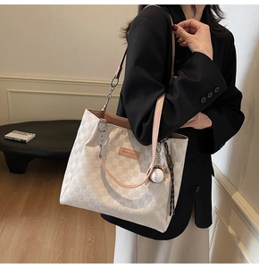 Close-up of white checkerboard tote bag with pink straps and fashion brand label detail
