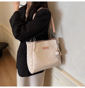 Detail of checkered tote bag with pink straps and a decorative baseball keychain