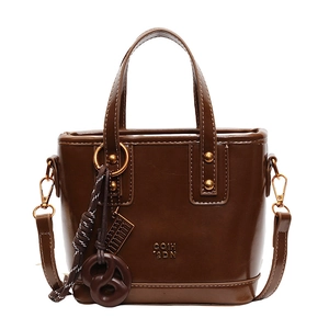 Deep brown glossy bucket bag with golden studs and a woven rope tassel detail