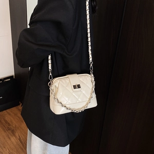 Sac bandoulière matelassé beige avec chaîne et fermoir pivotant sur mannequin