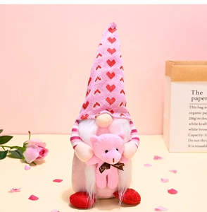 Detail of pink Valentine gnome holding a love bear with red heart pattern hat