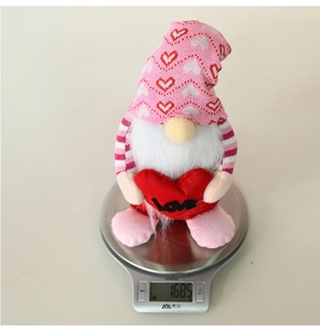 Close-up of pink heart gnome plush doll weighing 168.5 grams on a digital scale