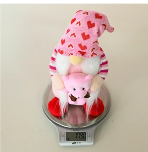 Close-up of pink heart-themed gnome plush being weighed at 179 grams on a scale