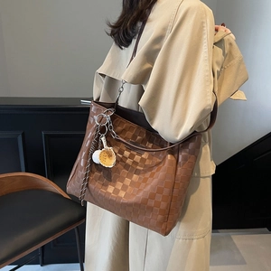 Brown checkered tote bag with baseball charm shown as a crossbody on a stylish trench coat