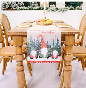 Detailaufnahme des beige Weihnachtstischläufers mit Wichtelprint und roten Bommeln