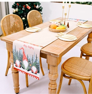 Detail eines Weihnachts-Tischläufers mit Gnomen und roten Pompons auf einem Holztisch