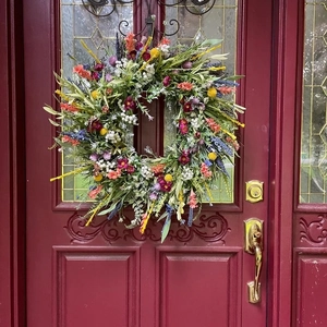 Dettaglio di ghirlanda di fiori selvatici del Texas appesa a una porta di legno rossa