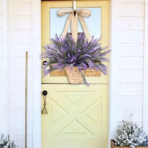 Couronne de panier de lavande avec fleurs violettes et nœud en toile sur une porte jaune