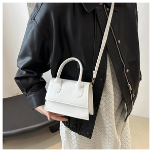 Detail of white mini handbag with round handle and detachable strap on leather jacket