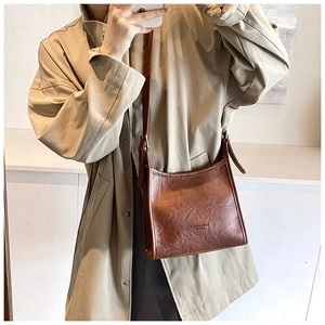 Detail of vintage brown leather crossbody bag featuring natural textured finish and metal buckle