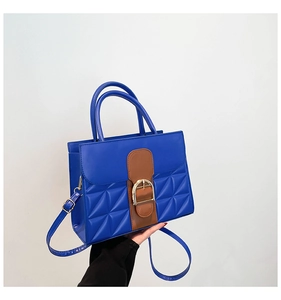 Détail du sac à bandoulière bleu avec boucle fer à cheval dorée et texture matelassée