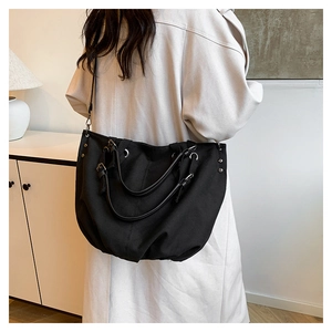 Macro detail of large black canvas tote bag with metal eyelets and adjustable strap