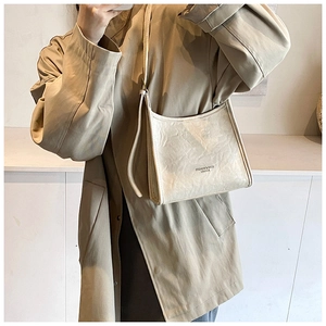 Close-up of beige pleated faux leather handbag with fine strap and printed logo detail