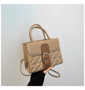 Détail d'un sac à main matelassé beige et marron avec boucle dorée en forme de D