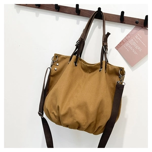 Close-up of khaki canvas tote with leather handle and vintage metal hardware details