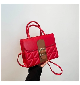 Détail du sac à main en cuir rouge avec surpiqûres géométriques et boucle fer à cheval