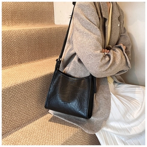Close-up of black pleated faux leather texture and embossed logo on the shoulder bag