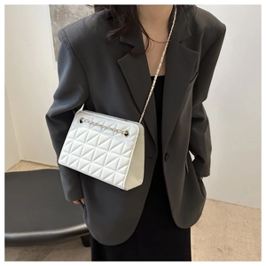 Close-up of white quilted crossbody bag with gold chain strap worn by a model