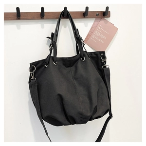 Detail of black canvas tote bag with adjustable shoulder strap and metal ring hardware