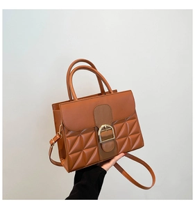 Détail du sac à main marron caramel montrant le matelassage et la boucle en D dorée