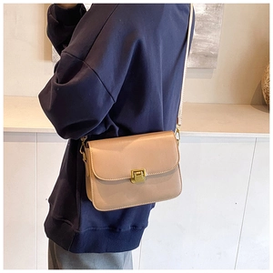 Beige leather crossbody bag with vintage gold metal buckle shown on a model