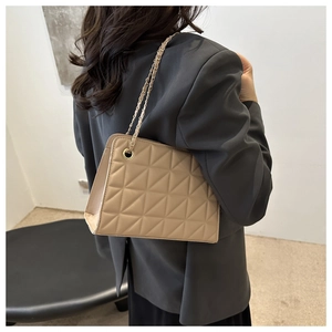 Detailed side view of beige quilted bag with gold-tone chain and woven leather strap