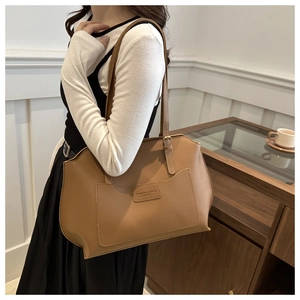 Détail du grand sac cabas en cuir marron montrant la bandoulière et le logo embossé